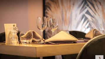 A dining table set with a water bottle, two wine glasses, a folded napkin, and a menu.