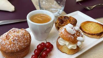 A dining table with a plate of pastries, a cup of coffee, and a glass of water.