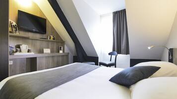 Una habitación de hotel moderna con una cama grande, un escritorio, un televisor de pantalla plana, una silla y una ventana con cortinas.