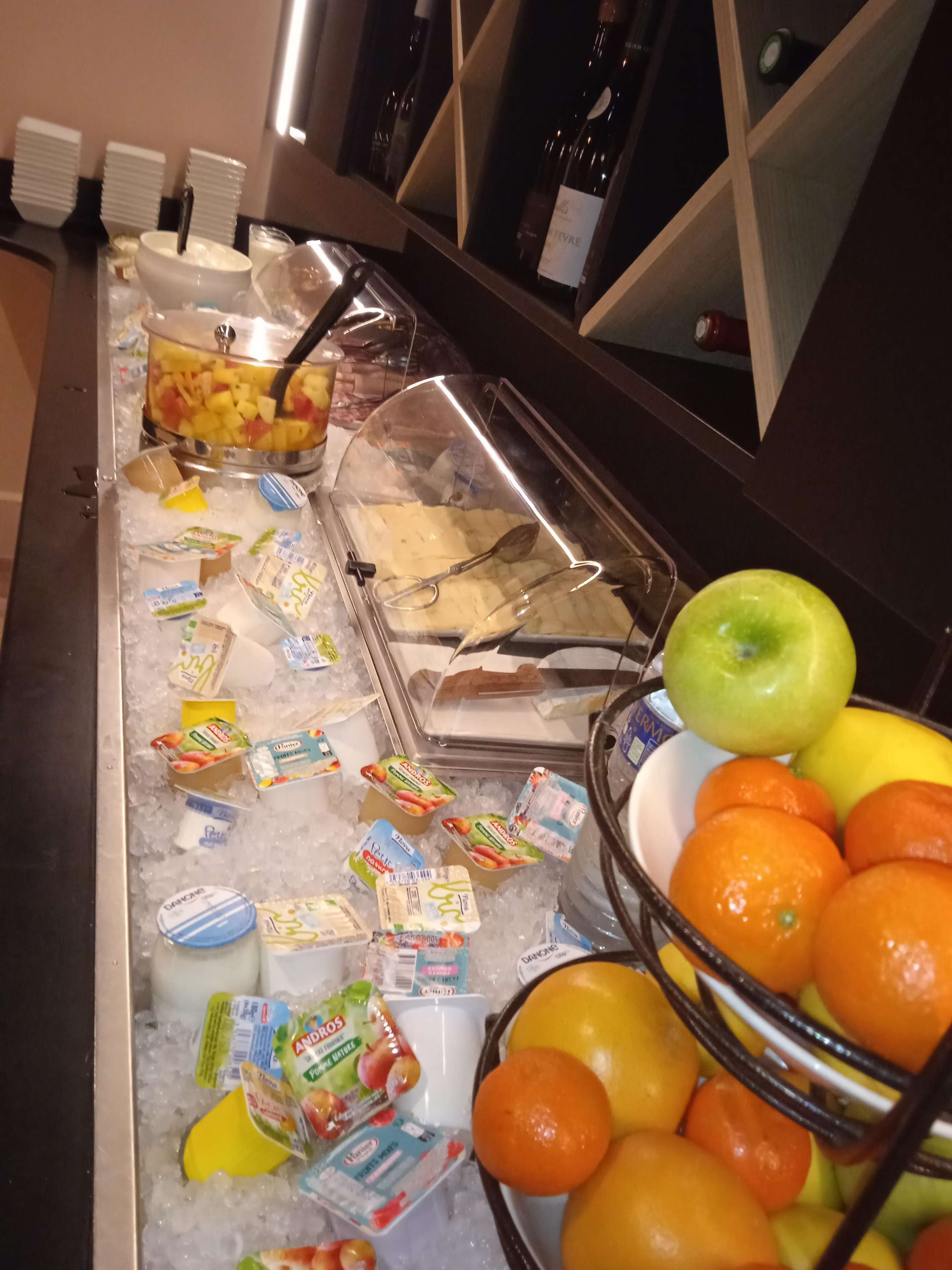 Een buffet met diverse gerechten, waaronder fruit, yoghurt en een schotel met ananasstukjes.
