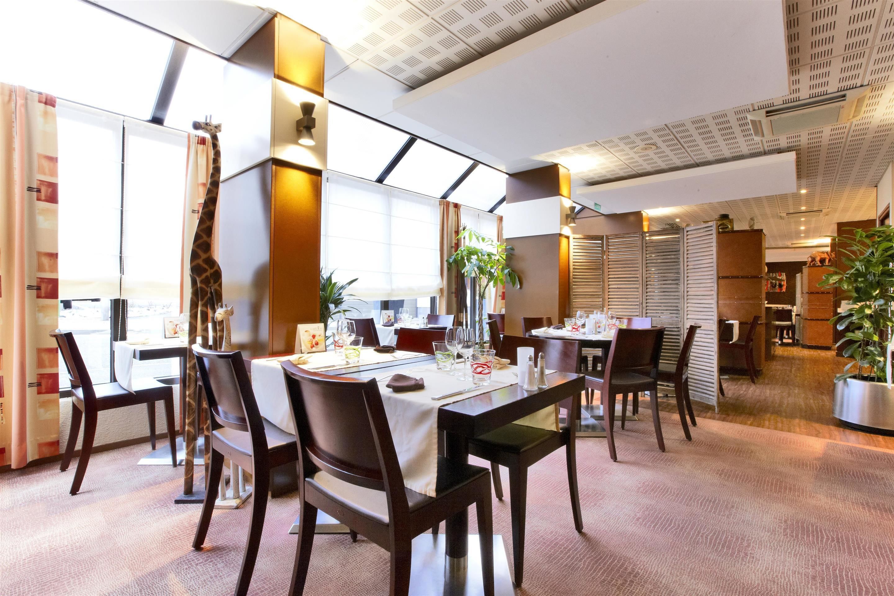 Comedor con mesas dispuestas para dos, con sillas de madera oscura y manteles blancos.