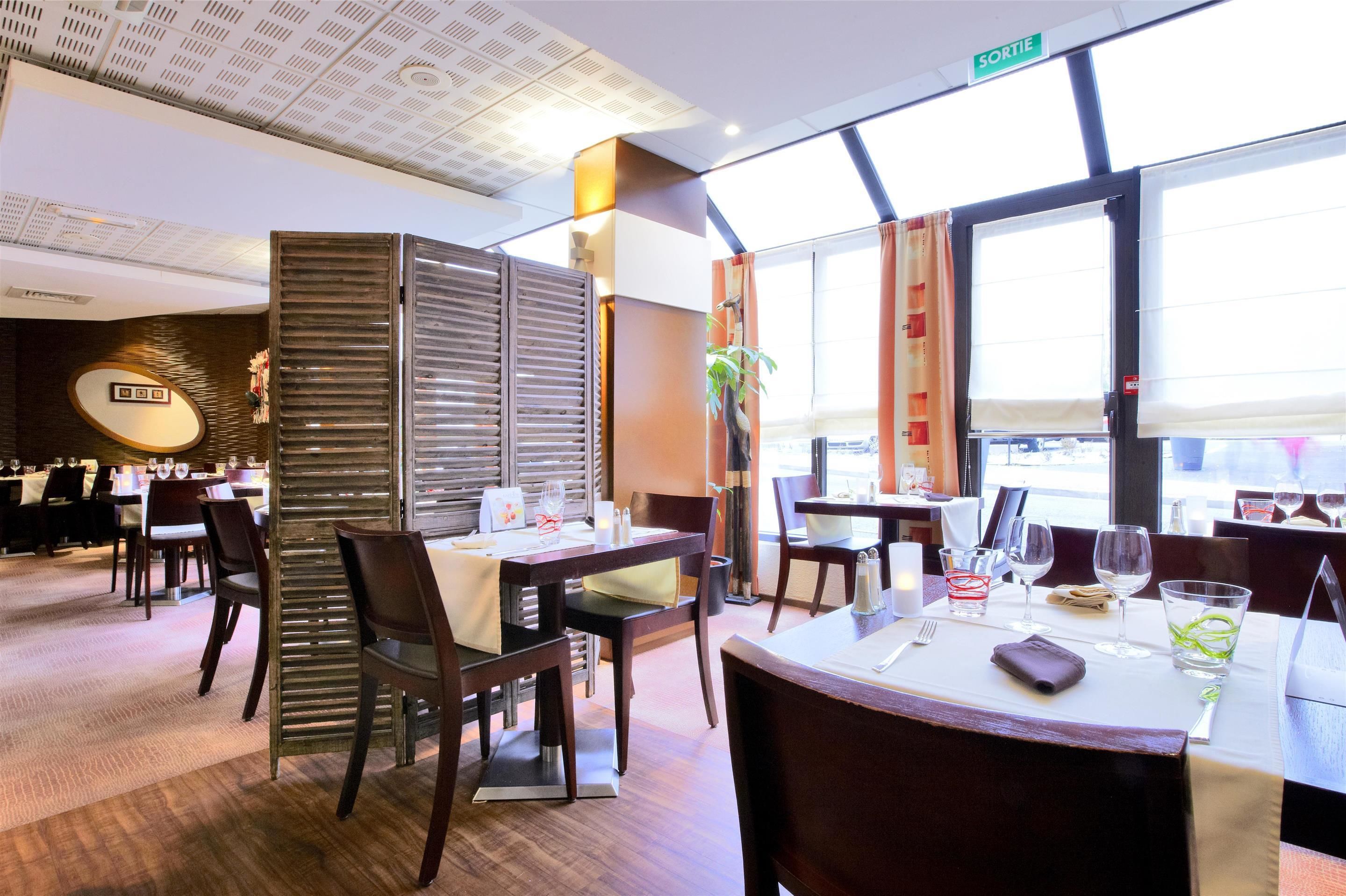 Un restaurant avec des tables dressées, un panneau indiquant la sortie et une plante en arrière-plan.