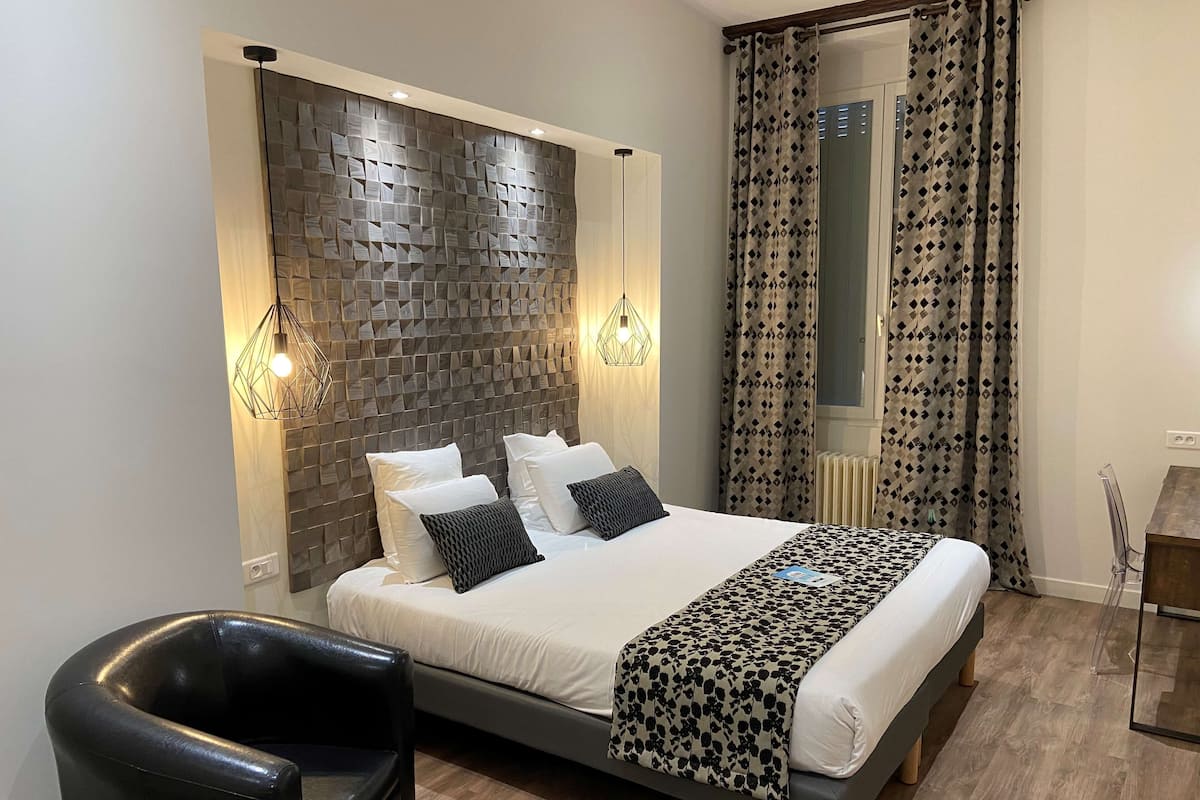Ein modernes Schlafzimmer mit einem großen Bett, einem schwarzen Ledersessel und einer gestreiften Tagesdecke.