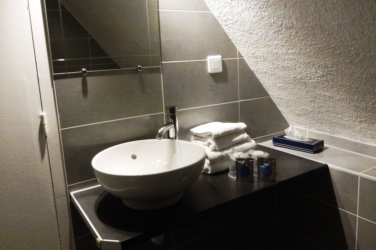 A bathroom with a white sink, dark tiles, and a towel rack.