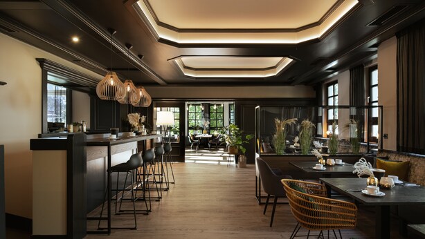 Un intérieur moderne avec un bar, des espaces pour s’asseoir et une vue sur l’extérieur.