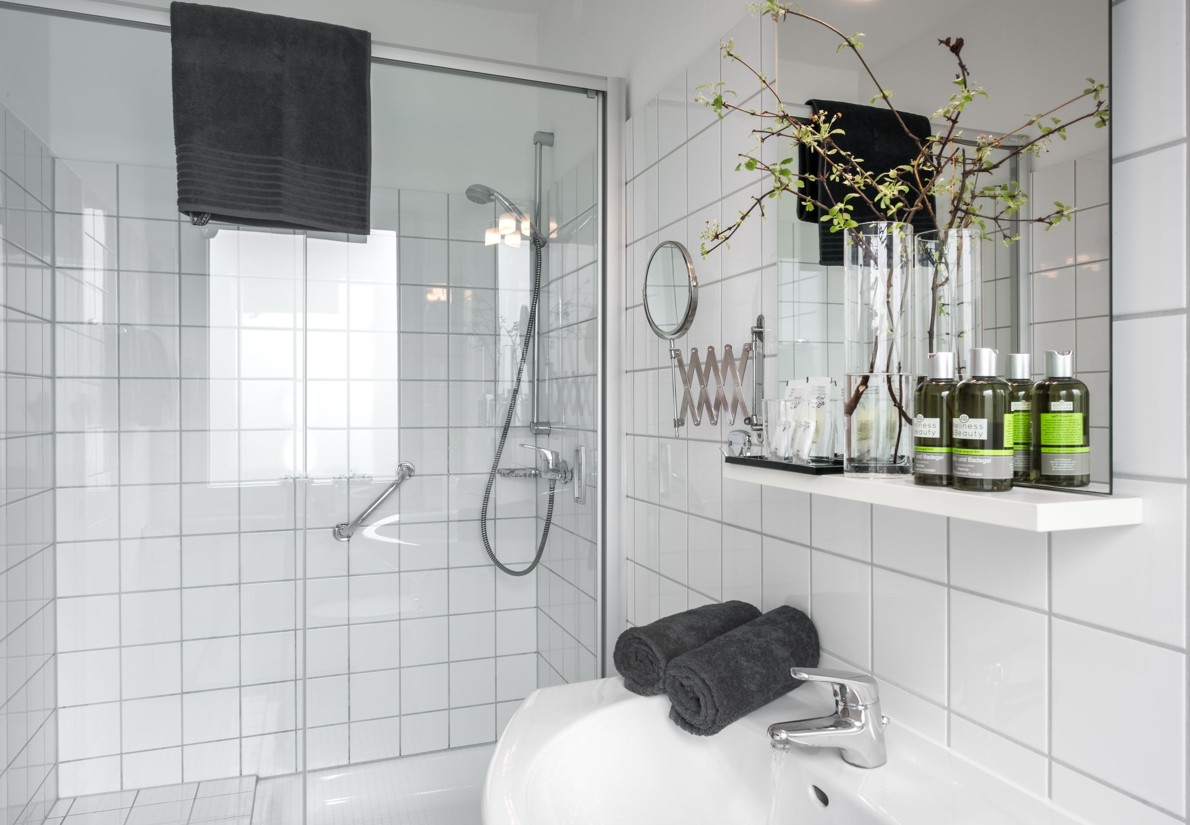 A modern bathroom with a glass-enclosed shower, a white sink, and a mirror above the mirror cabinet.