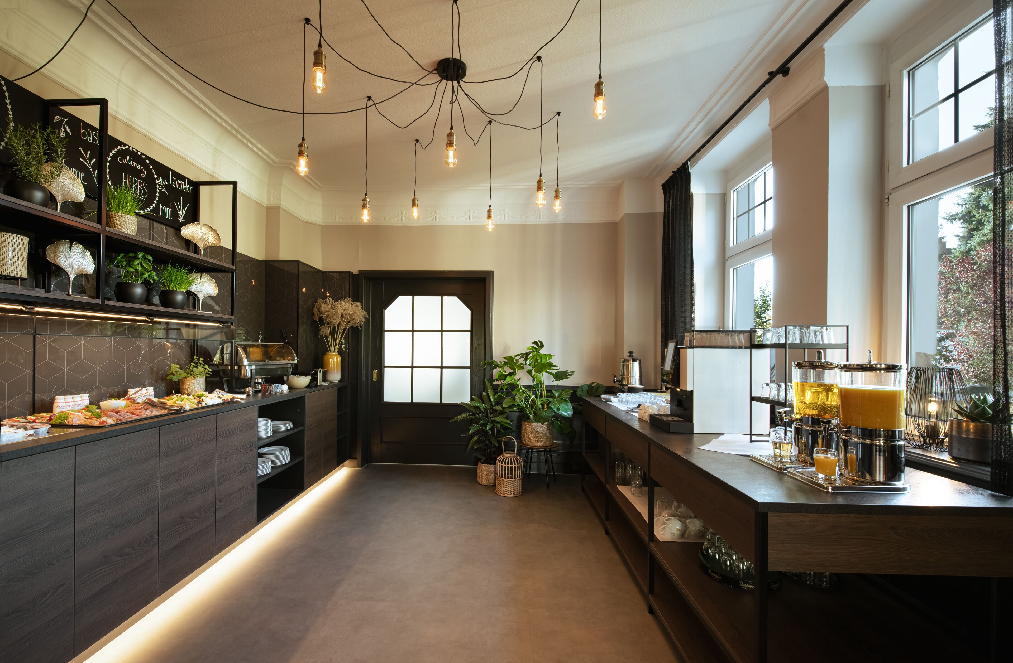 Cozinha moderna com ilha central, iluminação pendente e vista para o exterior.