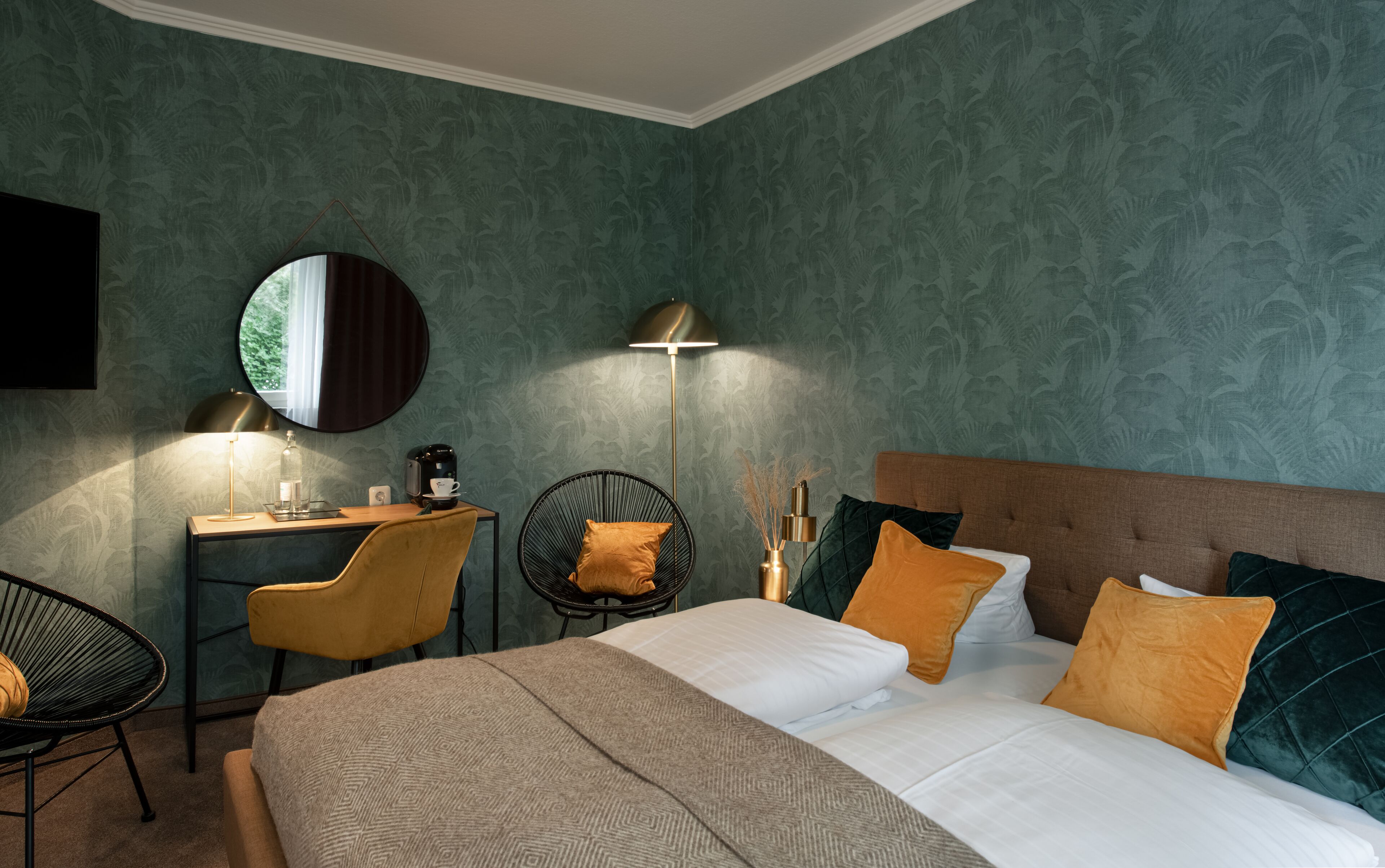 A hotel room with a bed, a desk, a chair, a lamp, and a coffee maker.