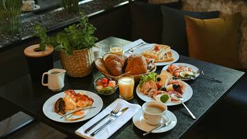 Una mesa de desayuno con diversos platos, una taza de café y una cesta de pan.
