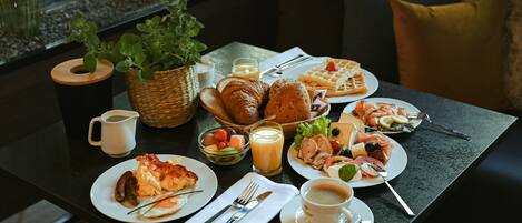 Una mesa de desayuno con diversos platos, una taza de café y una cesta de pan.
