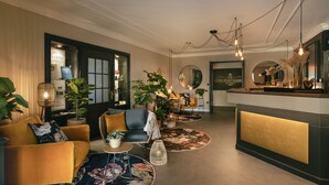 Un hall d’hôtel moderne avec un comptoir d’accueil, des sièges confortables et des plantes décoratives.