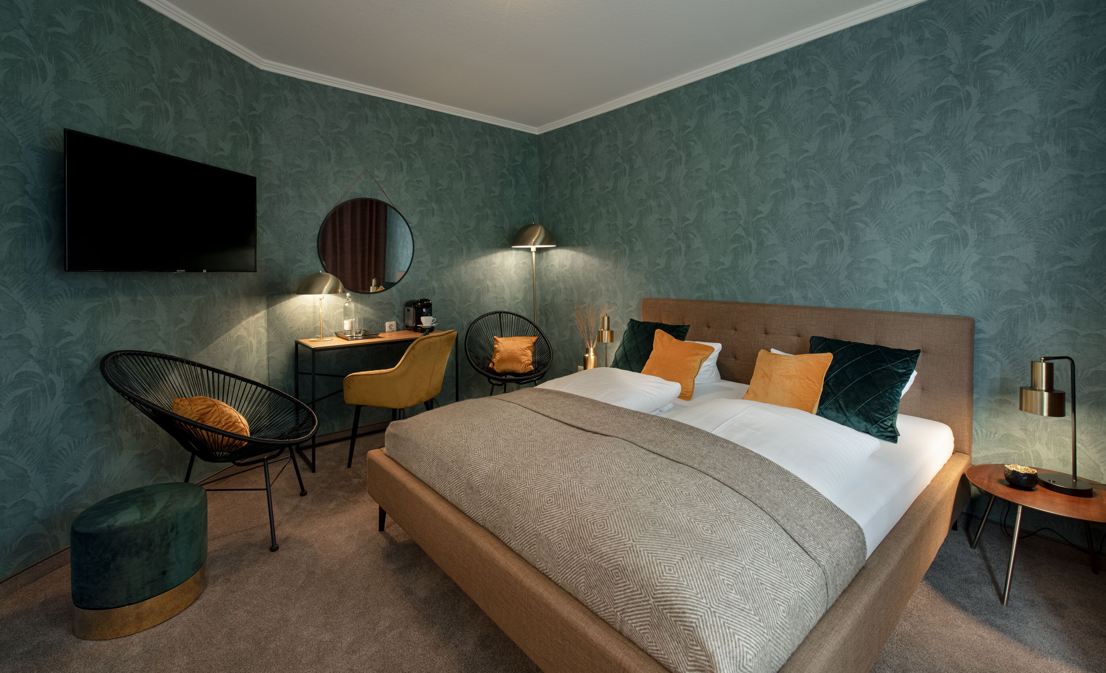 Un dormitorio moderno con una cama grande, un escritorio, una silla y un televisor instalado en la pared.