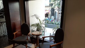 Una zona de estar con dos sillas, una mesita pequeña, una planta en maceta y vistas a la calle.