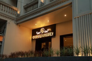 The exterior of the Golden Tower hotel with a prominent illuminated sign, a balcony with plants, and a classical architectural design. - Hotel Golden Tower (Amritsar)