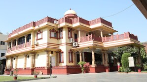 A multi-story building with a central dome, balconies with intricate railings, and a flat roof. - Hotel Siddhartha Palace (Ahmedabad)
