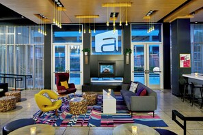 A modern lounge area with a fireplace, comfortable seating, and large windows offering views of the city.