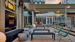 An outdoor patio with seating, a fireplace, and a view of the building's interior.