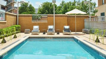 A swimming pool with lounge chairs and a fence.