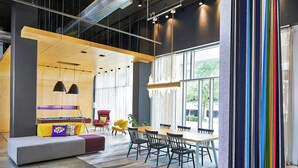 A modern interior with a long table, chairs, a sofa, and a large window.