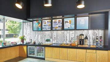 Interior moderno de una cafetería con mostradores de madera, un tablero de menú y una vitrina refrigerada.