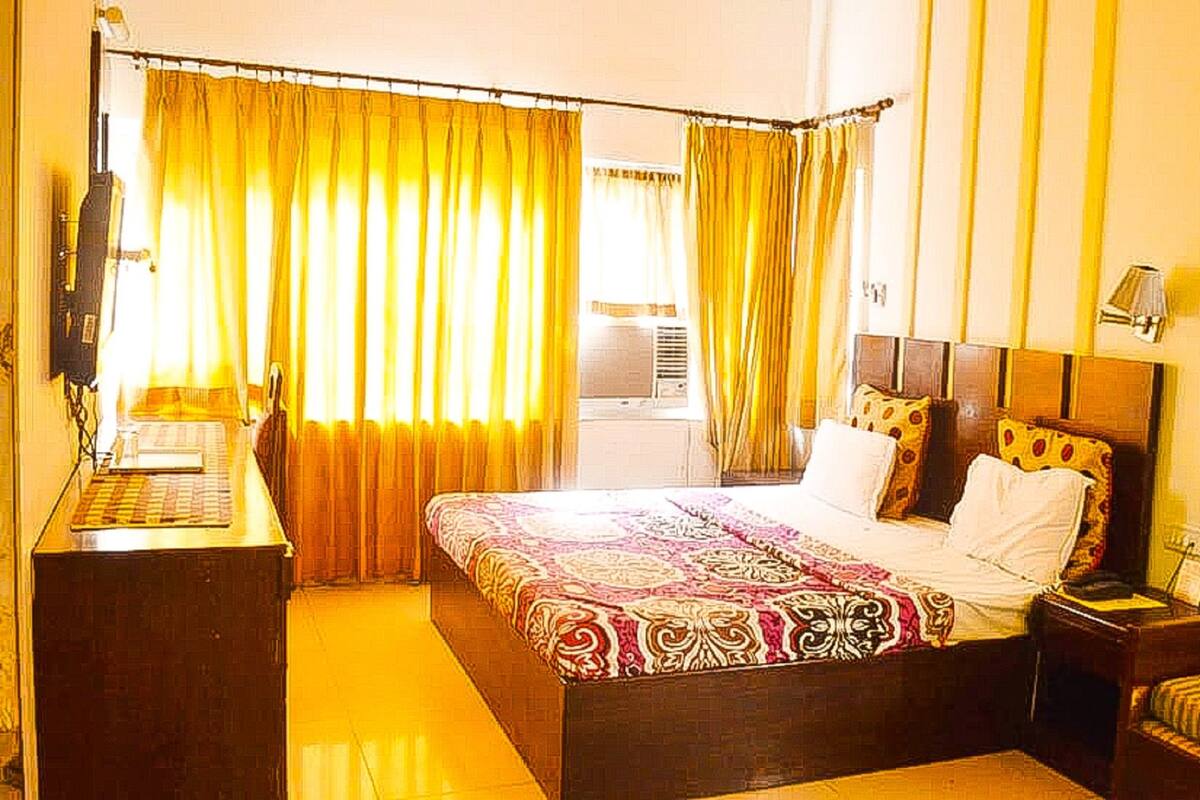 Habitación de hotel con cama, escritorio y silla. Hay una ventana con cortinas.