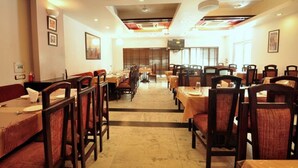 A spacious dining area with multiple tables and chairs, a central aisle, and a modern ceiling design. - Hotel Raj Darbar (Amritsar)