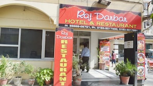Raj Darbar Hotel & Restaurant with a prominent signboard and potted plants in front. - Hotel Raj Darbar (Amritsar)
