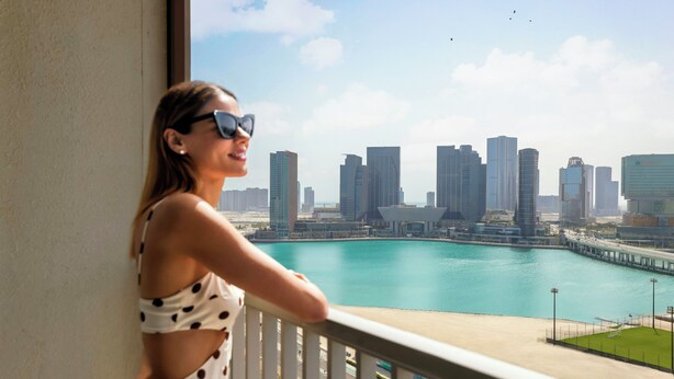 A balcony with a view of a city skyline and a body of water. - Hala Arjaan by Rotana (Abu Dhabi)