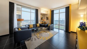 A modern living room with a sofa set, a glass coffee table, and a view of the city through large windows. - Hala Arjaan by Rotana (Abu Dhabi)