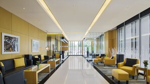 A modern lobby with a long reception desk, yellow and black seating, and large windows. - Hala Arjaan by Rotana (Abu Dhabi)