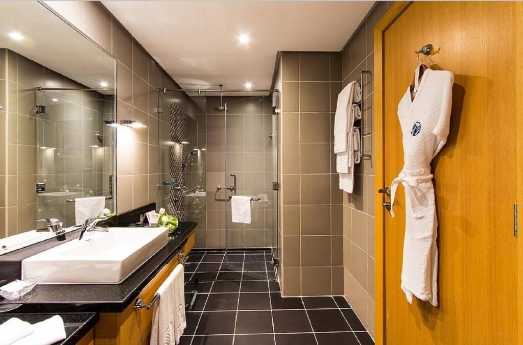 A modern bathroom with a large mirror, a sink, and a shower area.