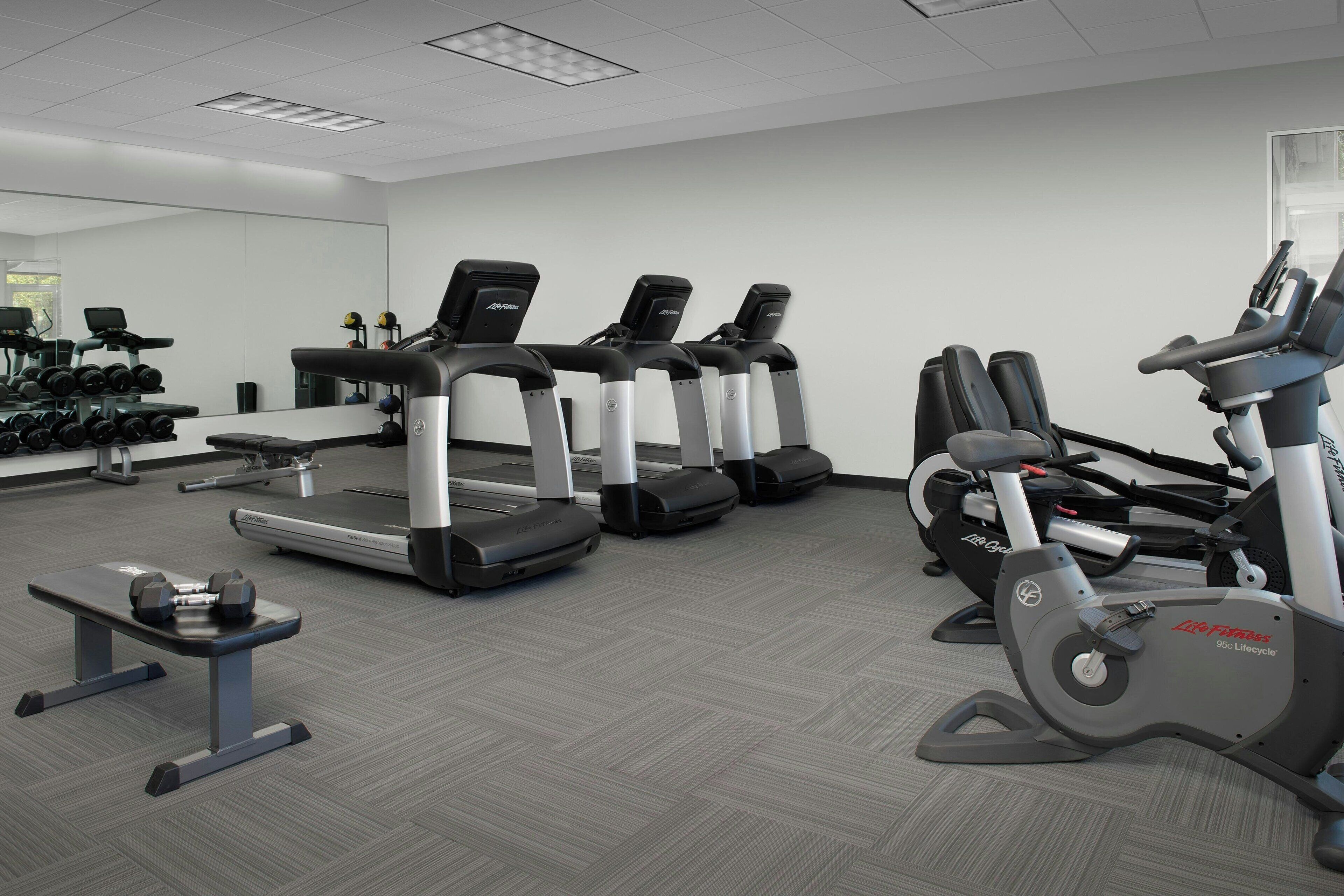 Een sportschool met loopbanden, een crosstrainer en losse gewichten.
