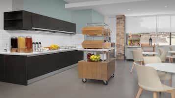 A modern kitchen with a central island, a coffee station, and a dining area with chairs and tables.
