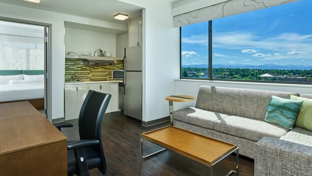 A modern living room with a sofa, a coffee table, and a dining area with a table and chairs. - Element by Marriott Denver Park Meadows (Lone Tree)
