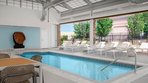A swimming pool area with lounge chairs and a table, large windows with a view of trees and a building, and a sculpture on the wall. - Element by Marriott Denver Park Meadows (Lone Tree)