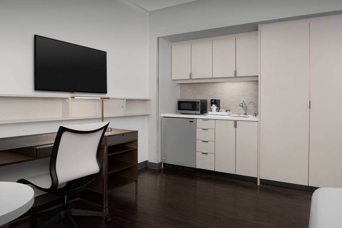A modern kitchen with white cabinets, a microwave, and a coffee maker.