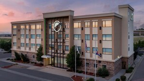A modern hotel building with a prominent circular logo on the facade, multiple windows, and flags. - Element by Marriott Denver Park Meadows (Lone Tree)
