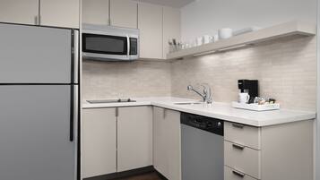 A modern kitchen with white cabinetry, a built-in microwave, a dishwasher, and a coffee maker on the countertop.