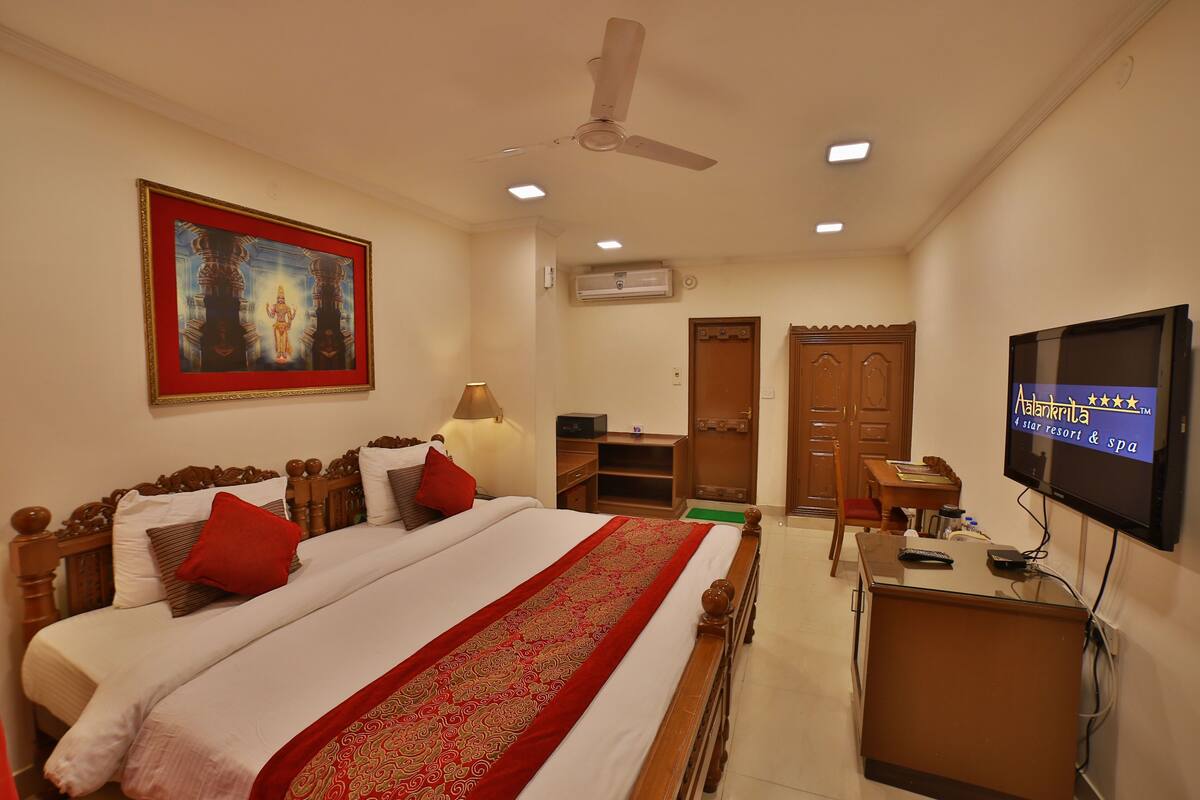 A hotel room with a bed, a desk, a TV, and a ceiling fan.