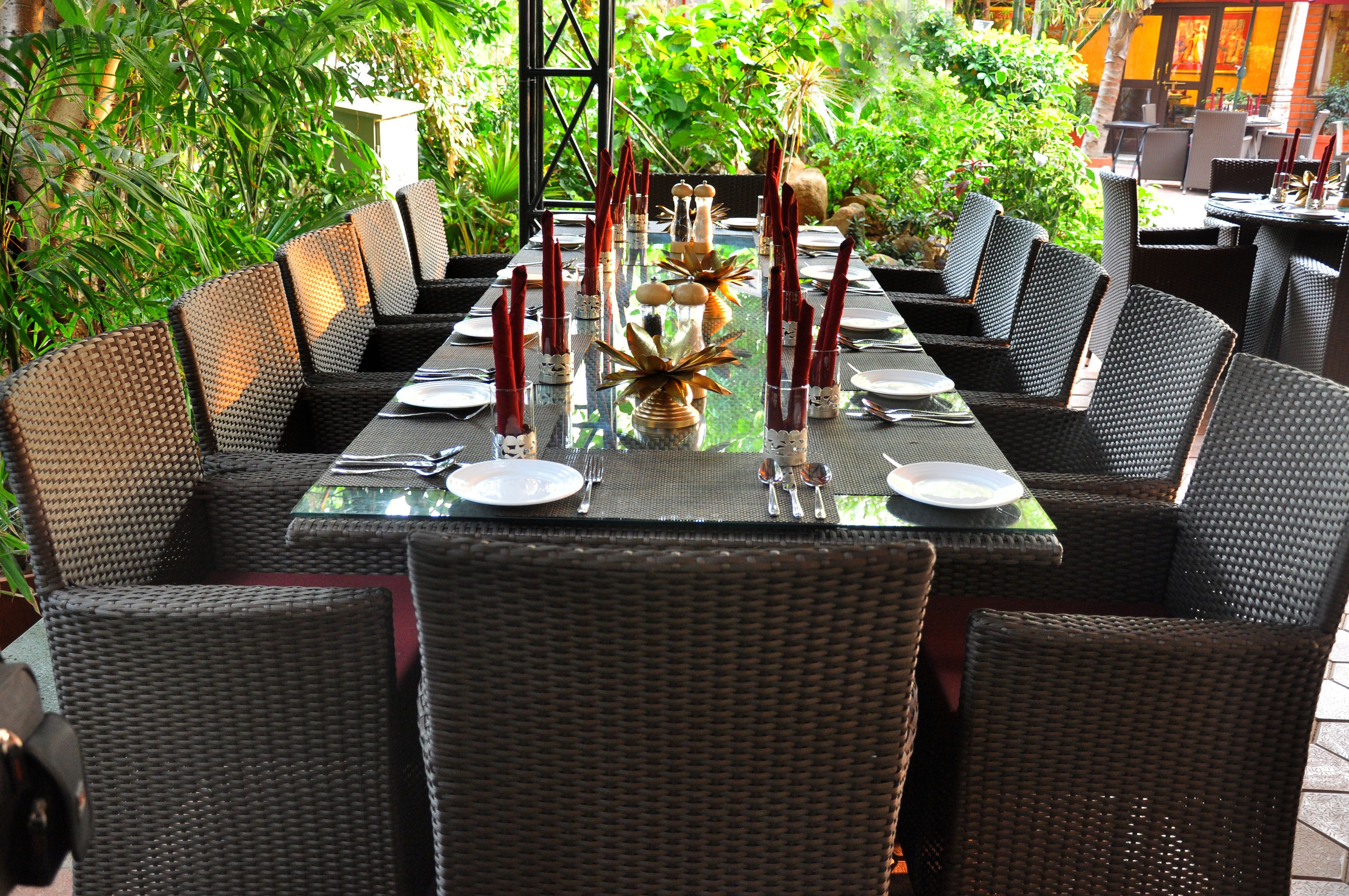 A dining area with wicker chairs and a glass table set for a meal.