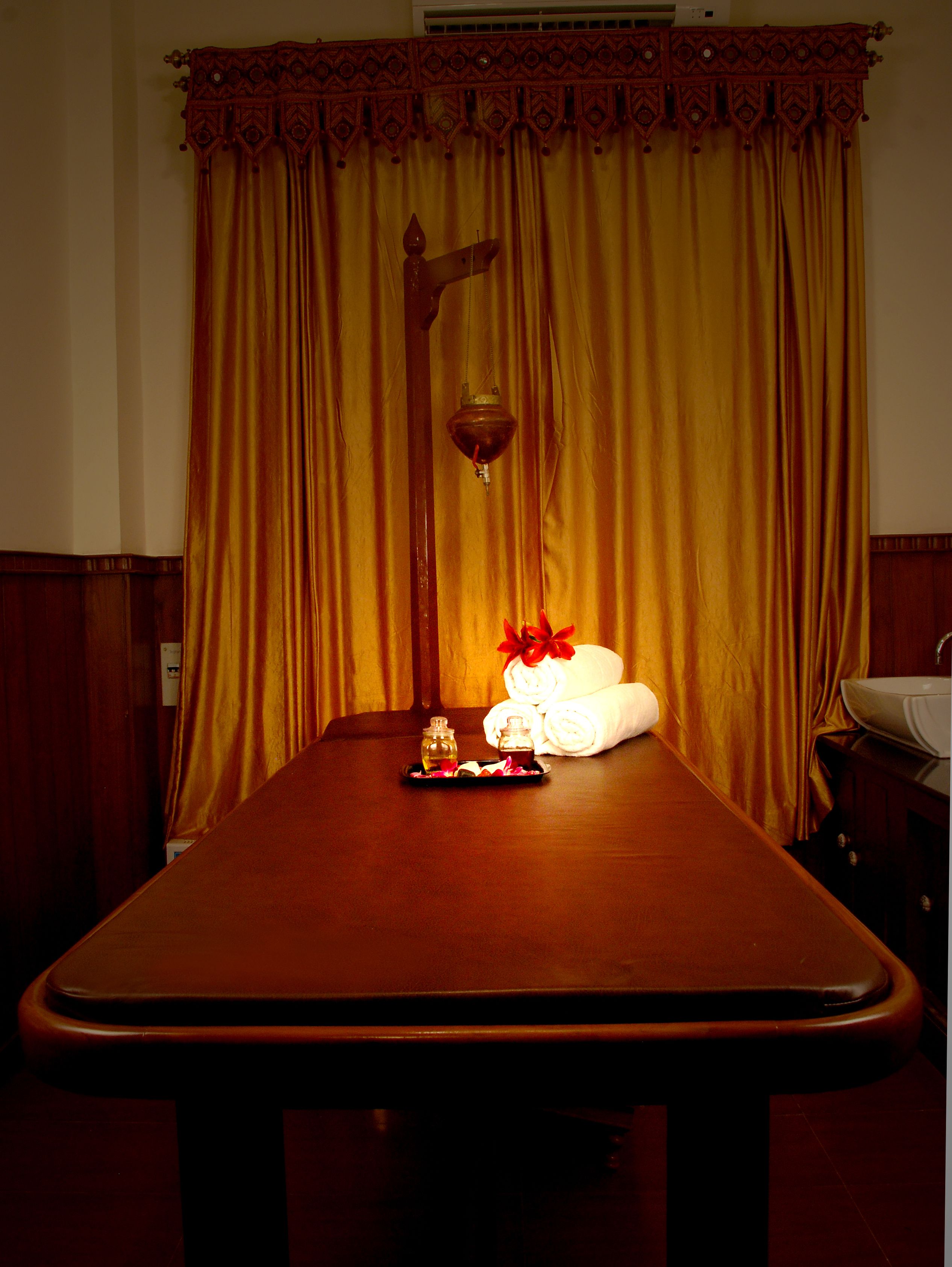 A room with a wooden table, a decorative hanging light, and a tray with towels and toiletries.