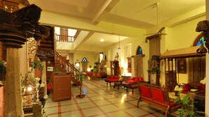 Eine großzügige Lobby mit Schachbrettfußboden, einer Treppe und verschiedenen Sitzgelegenheiten, darunter Sofas und Sessel.