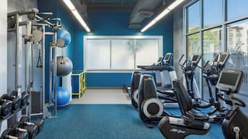 Een sportschool met trainingsapparatuur, een groot raam en een blauwe muur.