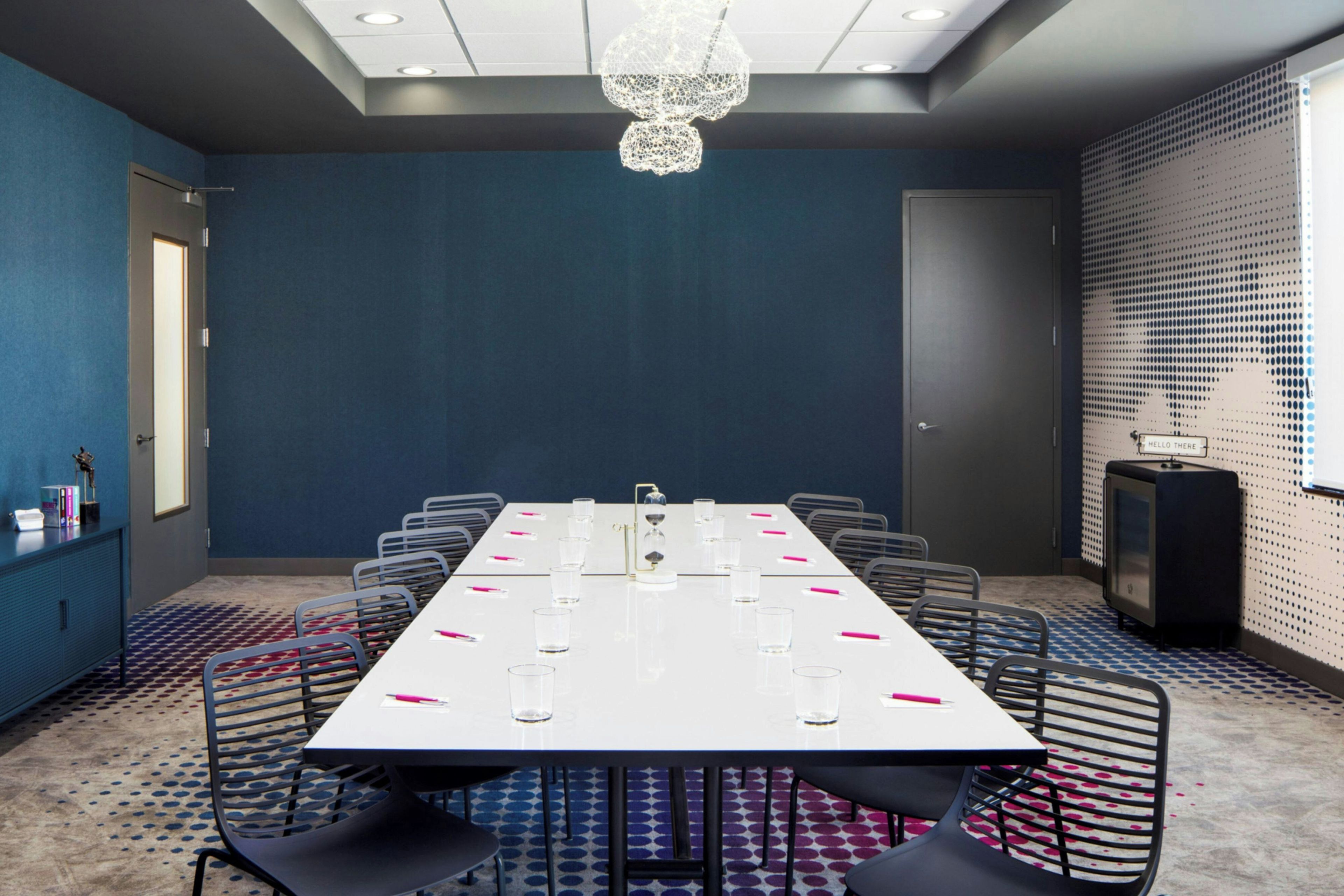 A conference room with a long table, chairs, a clock, and a decorative ceiling light.