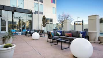 An outdoor seating area with sofas, tables, and potted plants.