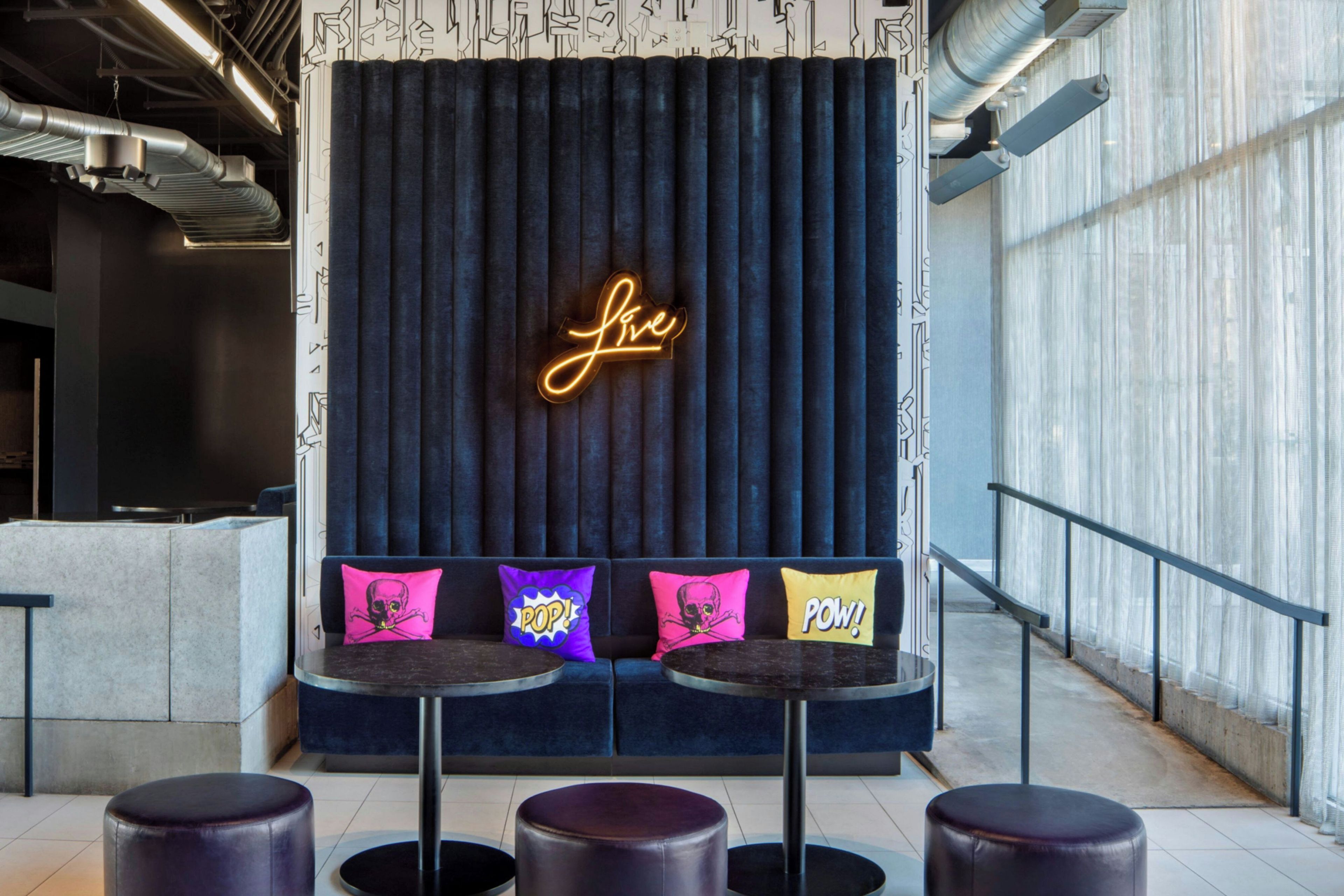 A seating area with a neon sign, cushioned seating, and a modern design.