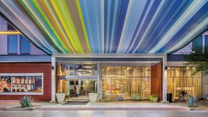 A modern hotel with a colorful striped ceiling, large windows, and a well-lit entrance. - Aloft by Marriott Phoenix-Airport (Phoenix)