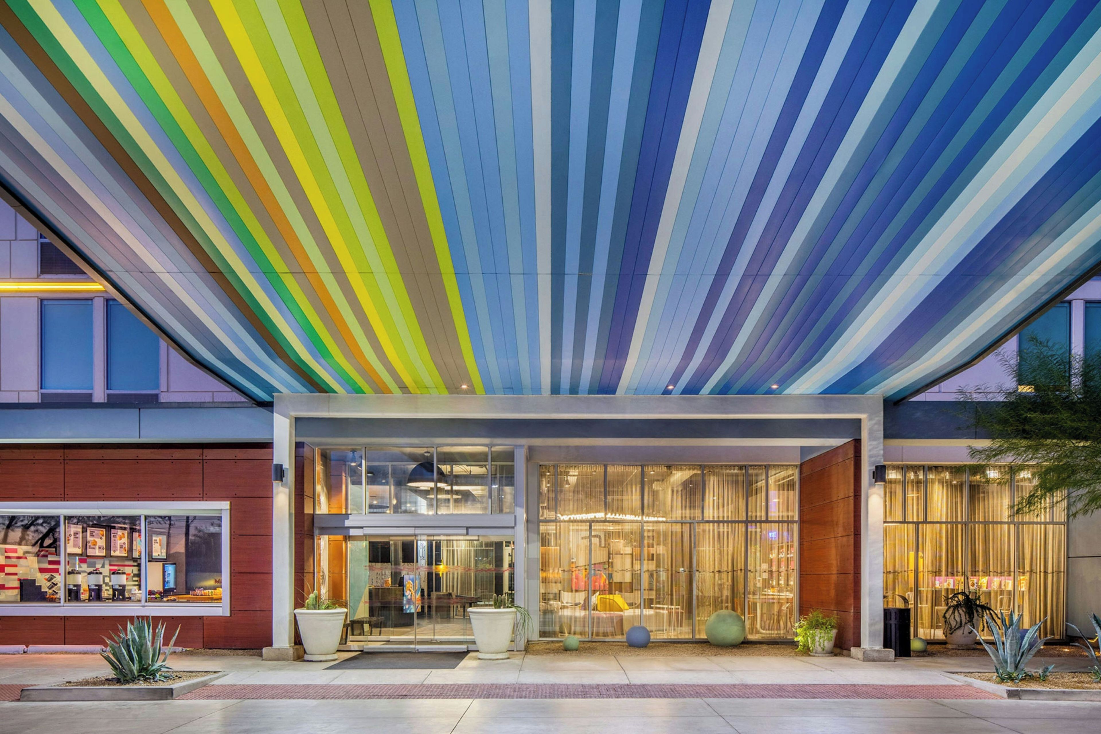 A modern building with a colorful striped ceiling, large windows, and a welcoming entrance.