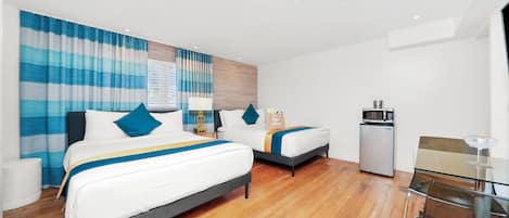 A hotel room with two beds, a small kitchenette, and a glass dining table.