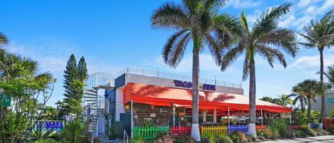 A restaurant with a red awning and a sign that reads "Taco Bar."